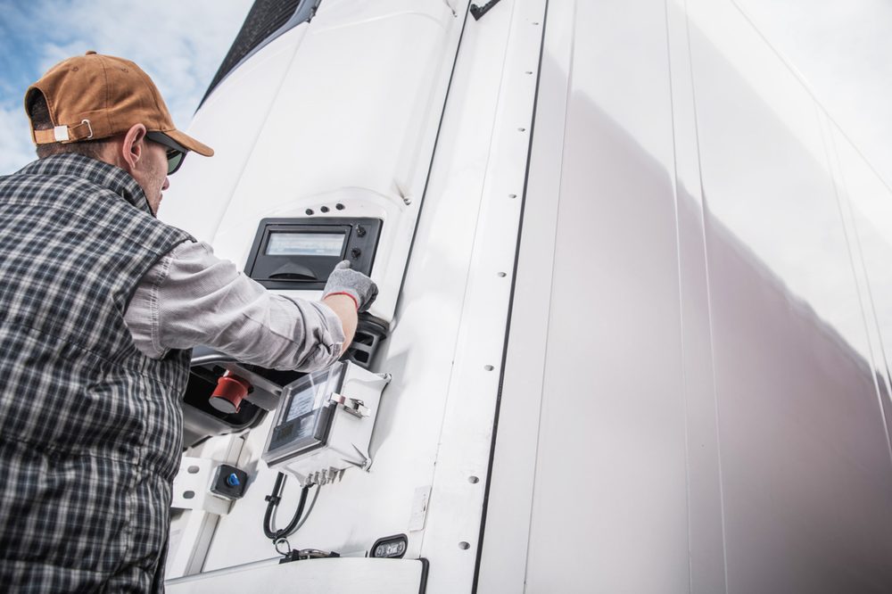 Driver checking the temperature readout on a refrigerated trailer unit